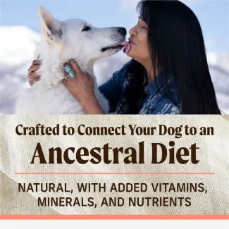 The top of the photo shows a white dog licking a woman's face. Text below reads "Crafted to connect your dog to an ancestral diet. Natural, with added vitamins, minerals and nutrients"